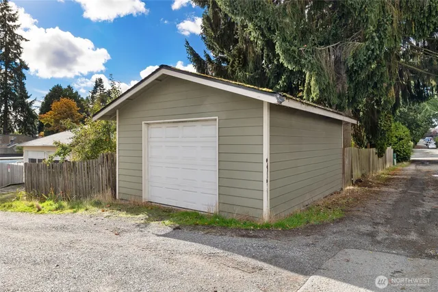 a view of a house with a yard plants and large tree