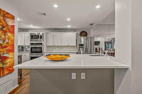 a view of a kitchen with kitchen island a sink a stove and a refrigerator