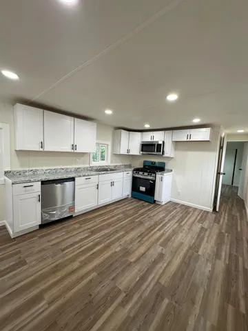 a kitchen with granite countertop a stove top oven a sink dishwasher and a refrigerator with wooden floor