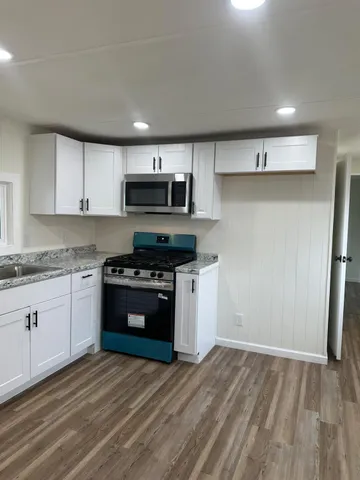a kitchen with granite countertop white cabinets and stainless steel appliances