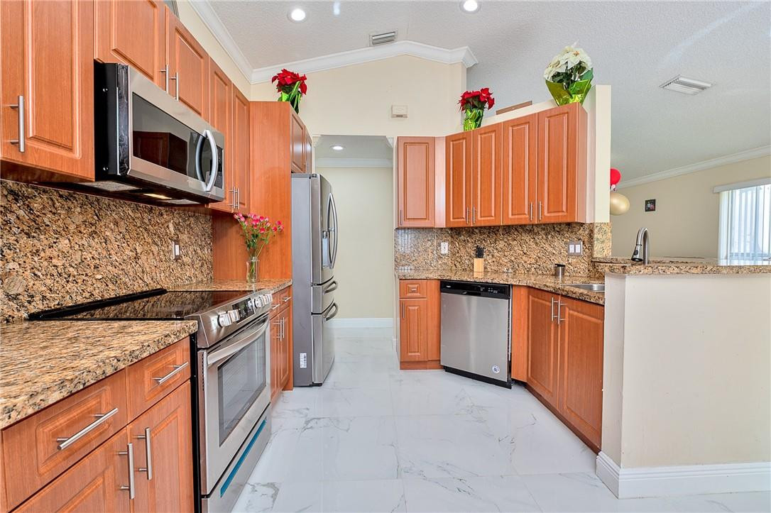 833 Falling Water Road Weston, FL 33326 - Photo 10 of 32 a kitchen with stainless steel appliances granite countertop a sink stove and microwave