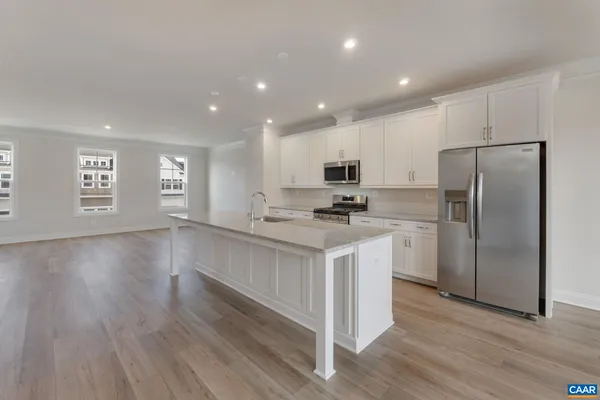 a kitchen with white cabinets and wooden floor