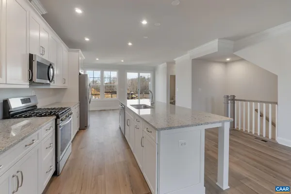 a large kitchen with stainless steel appliances granite countertop a lot of counter space and wooden floor