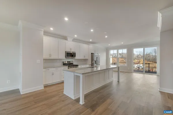 a kitchen with stainless steel appliances a stove a sink a refrigerator white cabinets and wooden floor