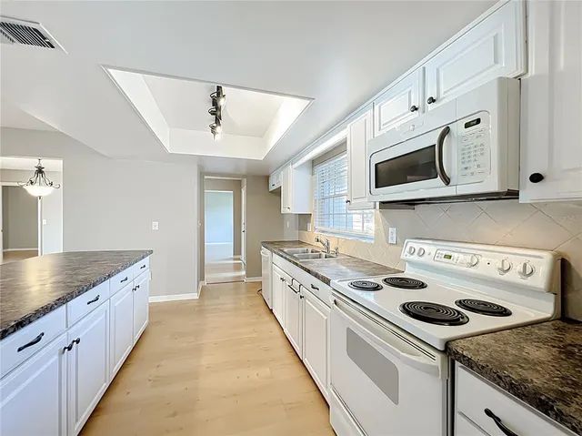 a kitchen with stainless steel appliances granite countertop a stove a sink and a microwave