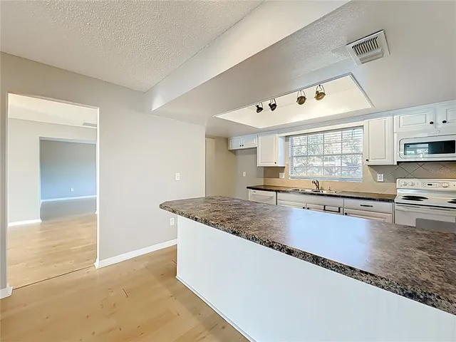 a kitchen with stainless steel appliances granite countertop a sink dishwasher and a stove with wooden floor