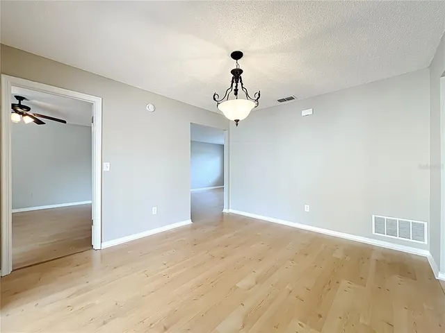 a view of an empty room with a chandelier fan