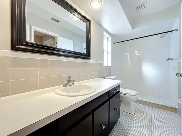 a bathroom with a sink a toilet a mirror and shower