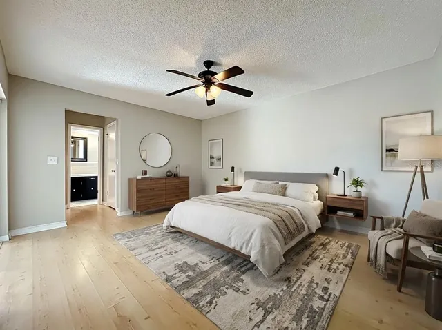 a spacious bedroom with a bed a mirror on dresser and a table