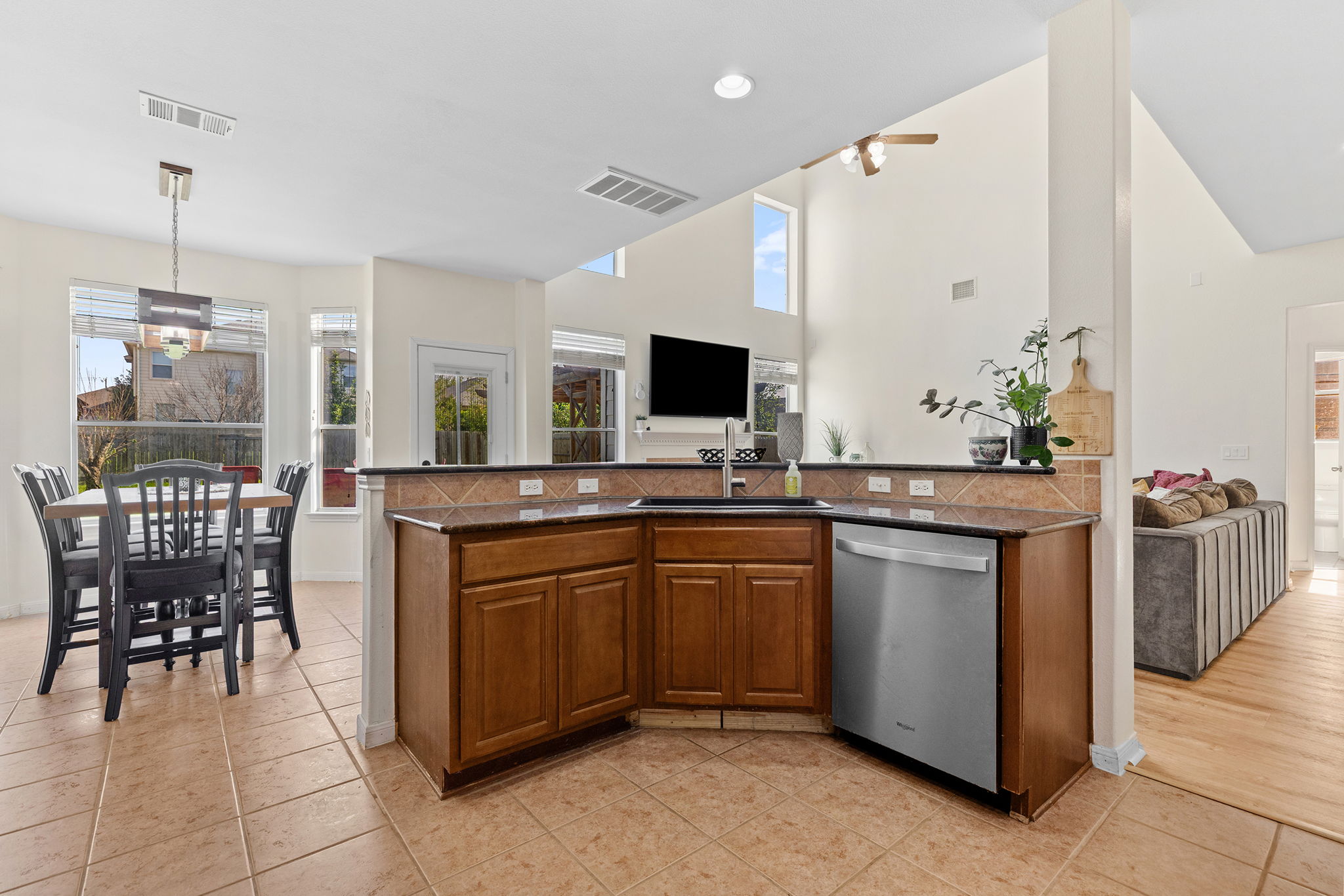 3517 Shiraz Loop Round Rock, TX 78665 - Photo 11 of 40 Open-concept kitchen with wood cabinetry and dark countertops, featuring a stainless steel dishwasher and a tiled backsplash