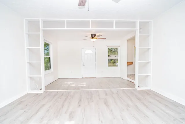 an empty room with windows and fan