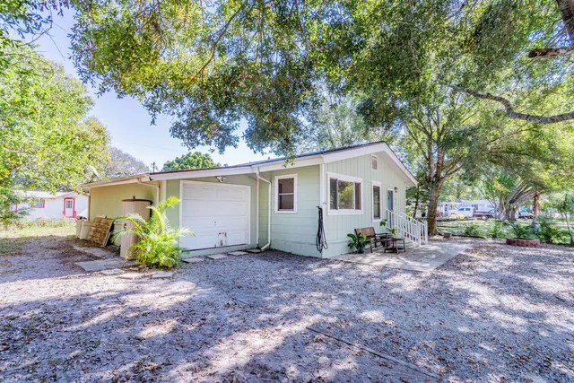 a view of a house with large trees and wooden fence