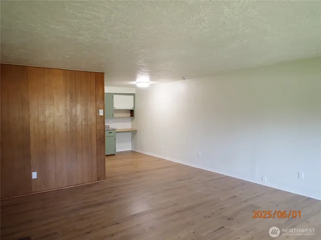 a view of an empty room with wooden floor and a cabinet