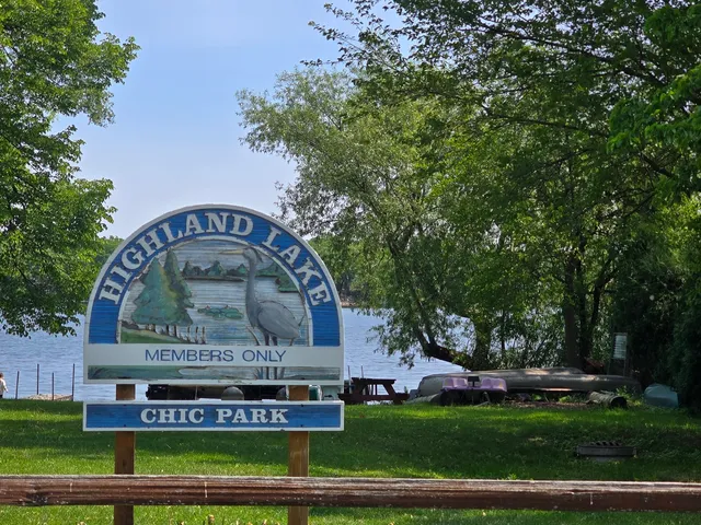 a view of a sign in a park with plants and trees