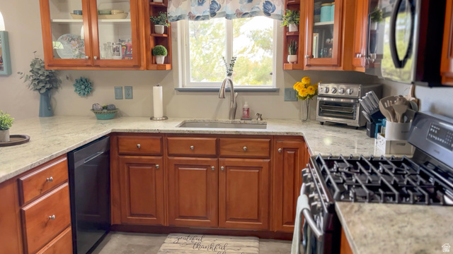 1797 Sunset Road Enoch, UT 84721 - Photo 14 of 80 U-shaped kitchen featuring wood-finish cabinetry, light-toned stone countertops, and a stainless steel sink with a gooseneck faucet