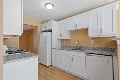 a kitchen with granite countertop a sink stainless steel appliances and white cabinets