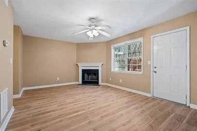 a view of an empty room with wooden floor and a window