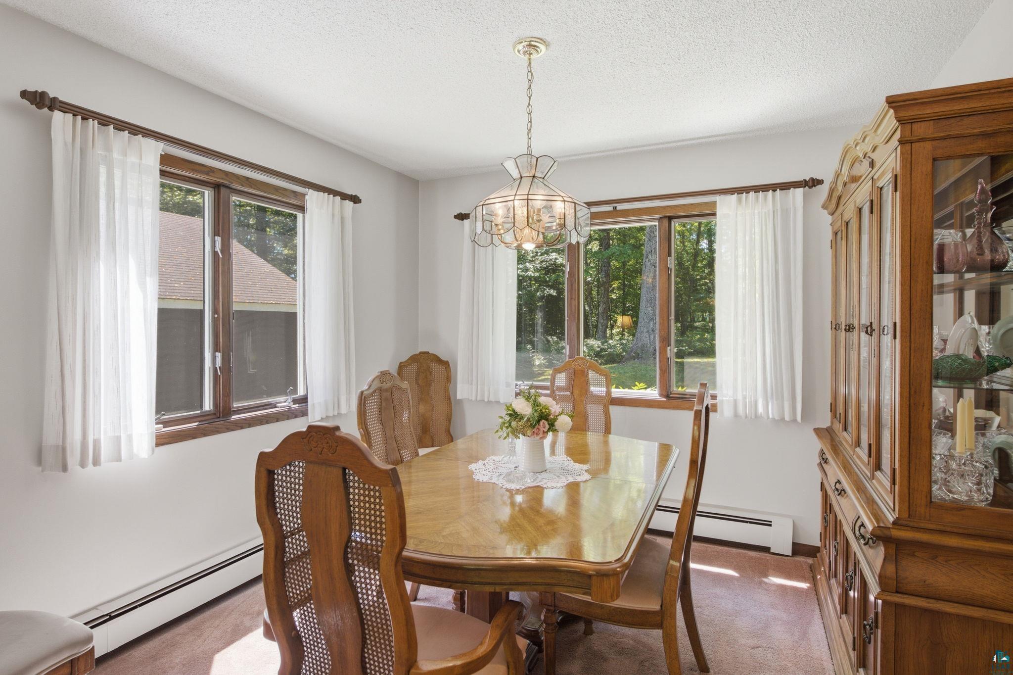 27485 South Kane Road Ashland, WI 54806 - Photo 12 of 35 Dining area with light-toned walls, wood-finish window trim, a glass-paneled built-in display cabinet, and a decorative ceiling light fixture