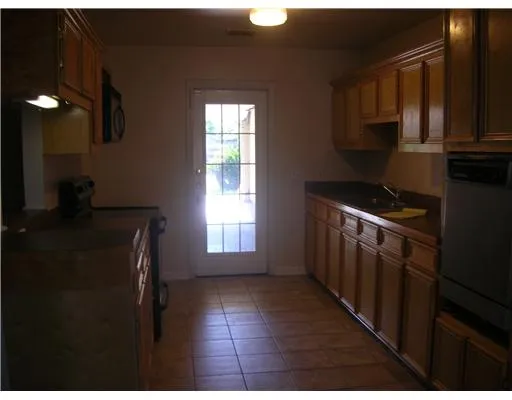 a kitchen with granite countertop a stove a sink a refrigerator and cabinets