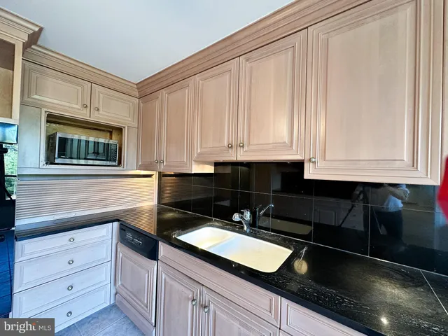 a kitchen with granite countertop white cabinets and black appliances