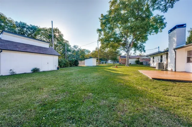 a view of a house with a big yard potted plants and large tree