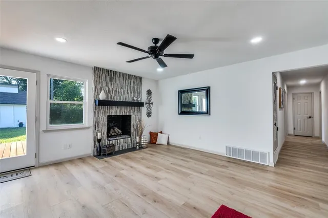 a view of a livingroom with a fireplace a ceiling fan and wooden floor