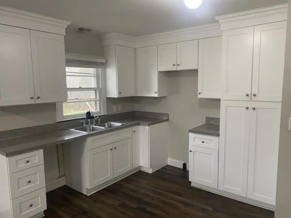 a kitchen with white cabinets and sink