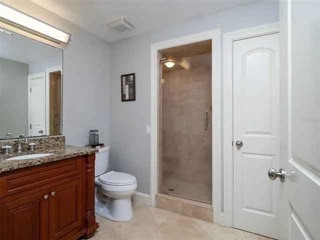 a bathroom with a granite countertop toilet a sink and a mirror
