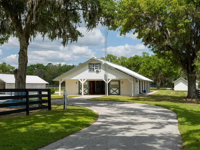 a front view of a house with garden and trees