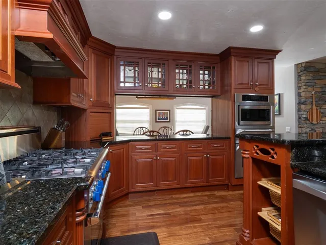 a kitchen with stainless steel appliances granite countertop a stove top oven a sink dishwasher and cabinets with wooden floor