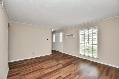 a view of an empty room with wooden floor and a window