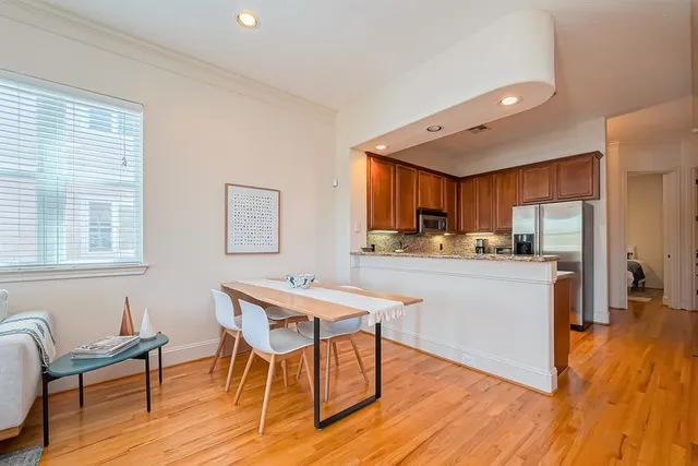 a kitchen with stainless steel appliances granite countertop a kitchen island hardwood floor sink stove dining table and chairs