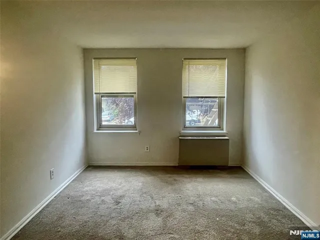 an empty room with windows and cabinet