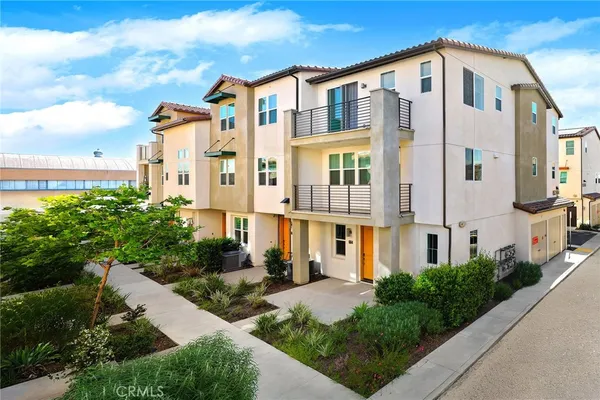a front view of a multi story residential apartment building with yard and parking spaces