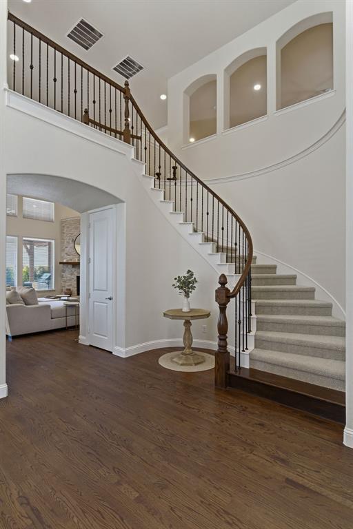 2801 Seabiscuit Road Celina, TX 75009 - Photo 21 of 39 Stairs with a high ceiling, arched walkways, wood finished floors, and a large fireplace