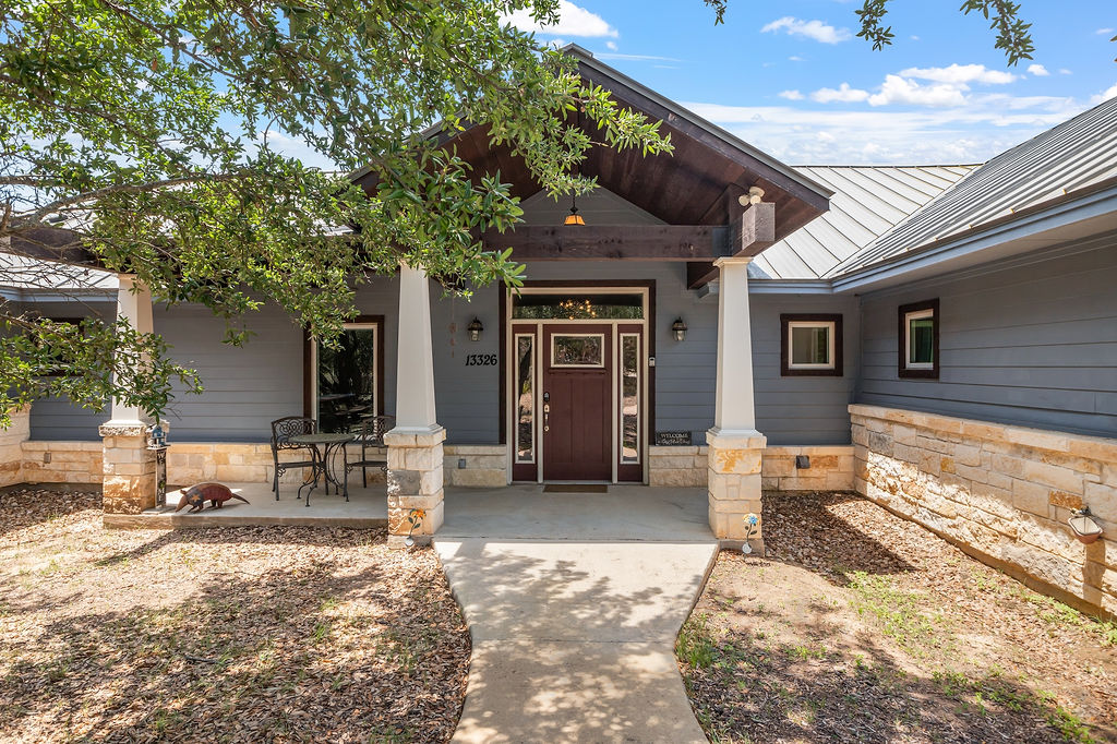 Doorway to property with a porch, a standing seam roof, metal roof, and stone siding