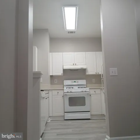 a kitchen with a stove top oven and white cabinets