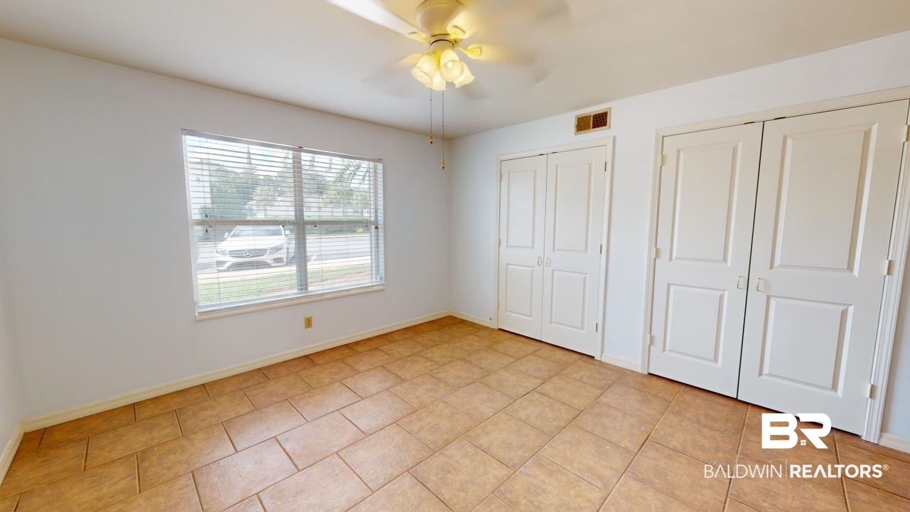 4009 Old Shell Road, Unit C13 Mobile, AL 36608 - Photo 14 of 32 Unfurnished bedroom featuring two closets, baseboards, light tile patterned floors, and ceiling fan