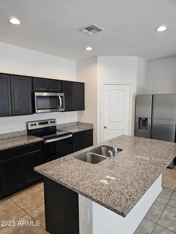 a kitchen with stainless steel appliances granite countertop a sink stove and refrigerator
