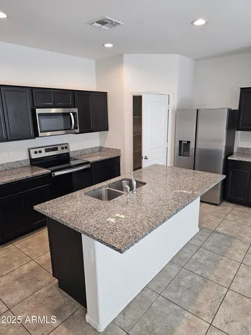 a kitchen with stainless steel appliances granite countertop a sink a stove top oven and refrigerator