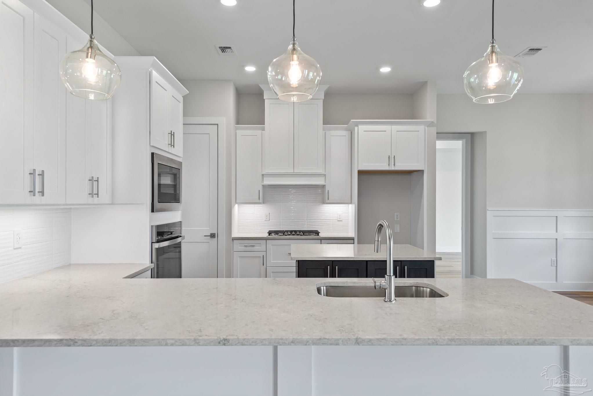 2038 Fontainebleau Court Navarre, FL 32566 - Photo 3 of 8 a kitchen with kitchen island white cabinets and refrigerator