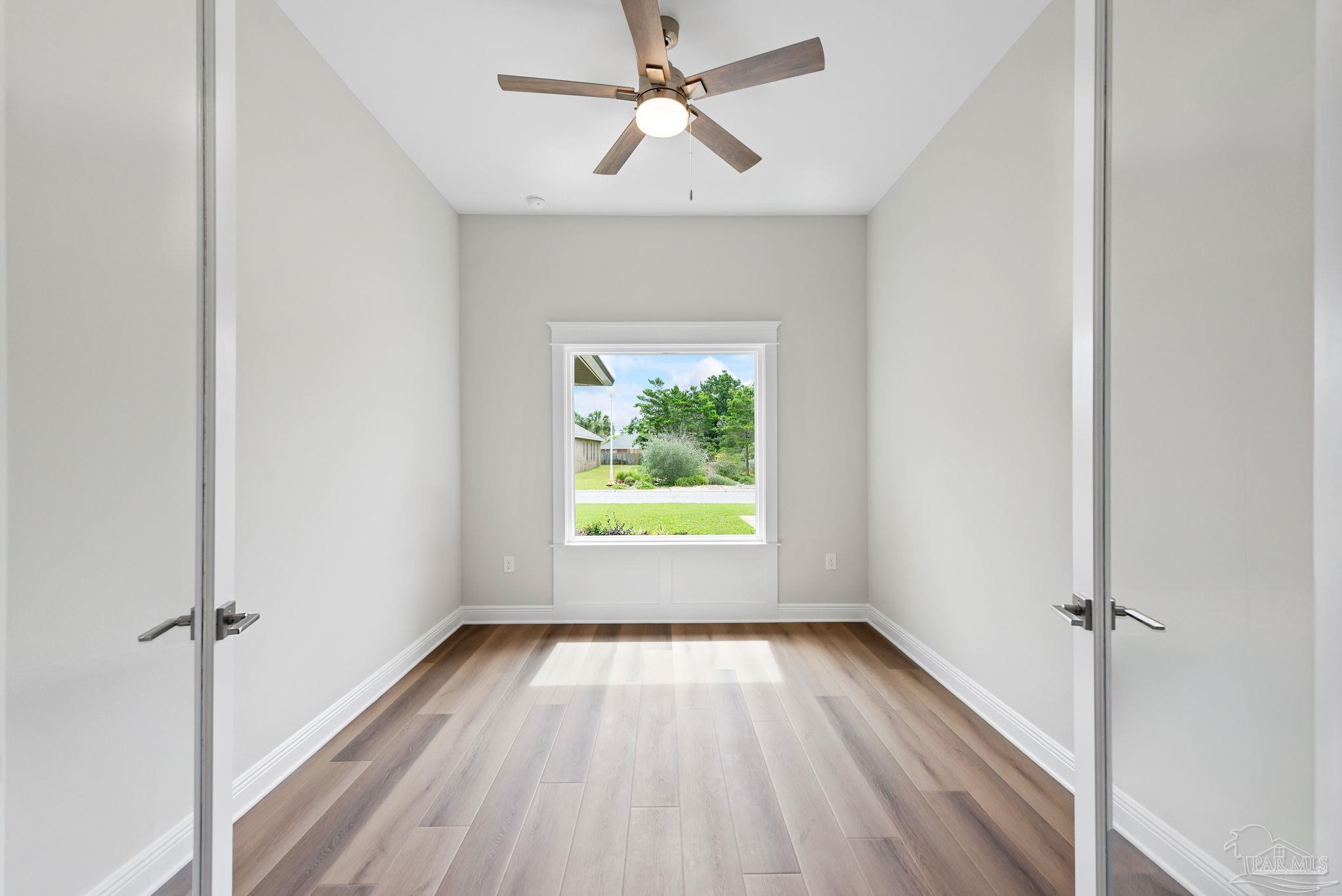 2038 Fontainebleau Court Navarre, FL 32566 - Photo 7 of 8 wooden floor in an empty room with a window