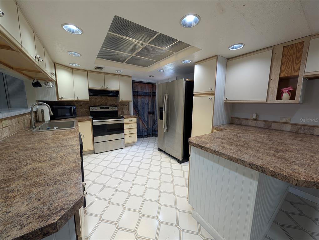 5508 Bryson Drive Orlando, FL 32818 - Photo 36 of 69 a kitchen with stainless steel appliances kitchen island granite countertop a sink a stove and cabinets