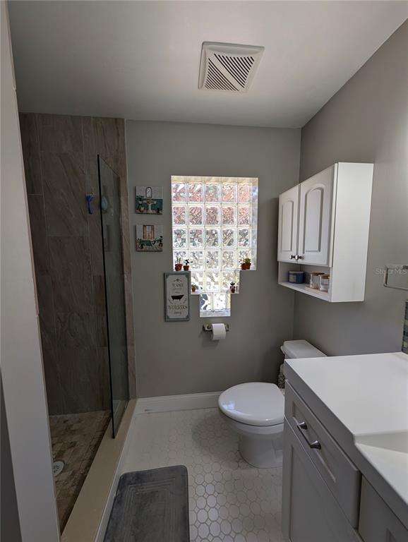 5508 Bryson Drive Orlando, FL 32818 - Photo 41 of 69 a bathroom with a granite countertop toilet a sink a mirror and a shower