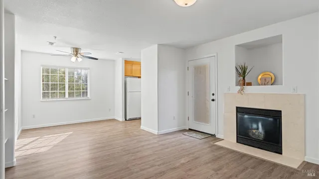 an empty room with wooden floor fireplace and window