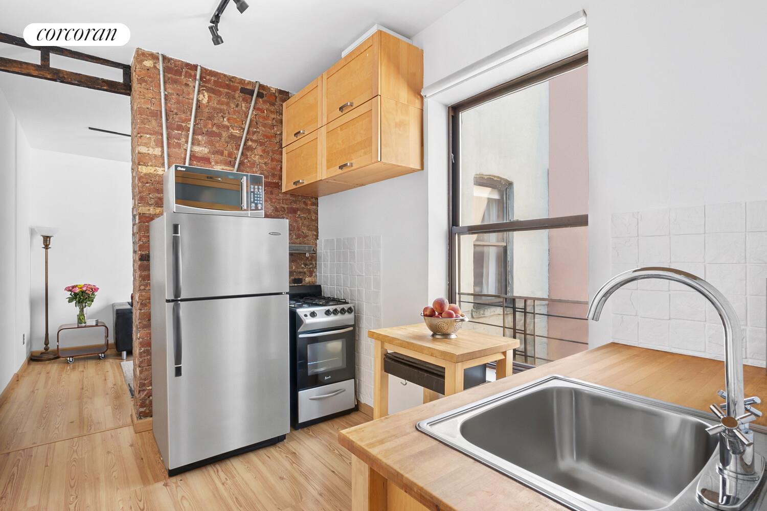 311 East 3rd Street, Unit 33 Manhattan, NY 10009 - Photo 4 of 7 a kitchen with stainless steel appliances a refrigerator sink and cabinets