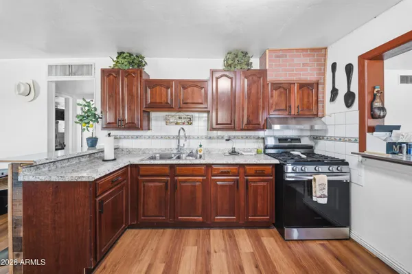 a kitchen with stainless steel appliances granite countertop wooden cabinets a sink and dishwasher a stove with wooden floor