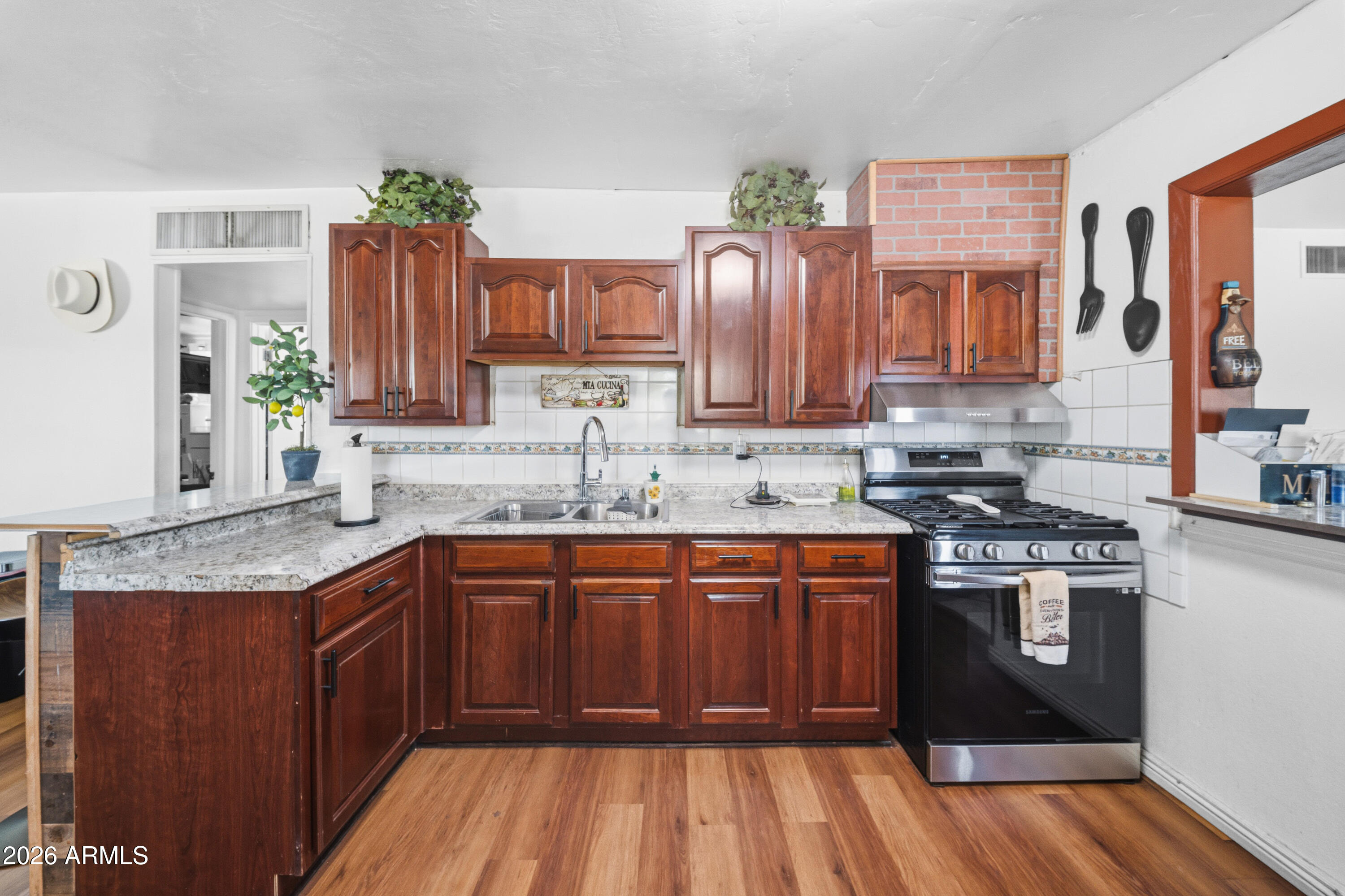 3902 West Monte Vista Road Phoenix, AZ 85009 - Photo 4 of 29 a kitchen with stainless steel appliances granite countertop wooden cabinets a sink and dishwasher a stove with wooden floor