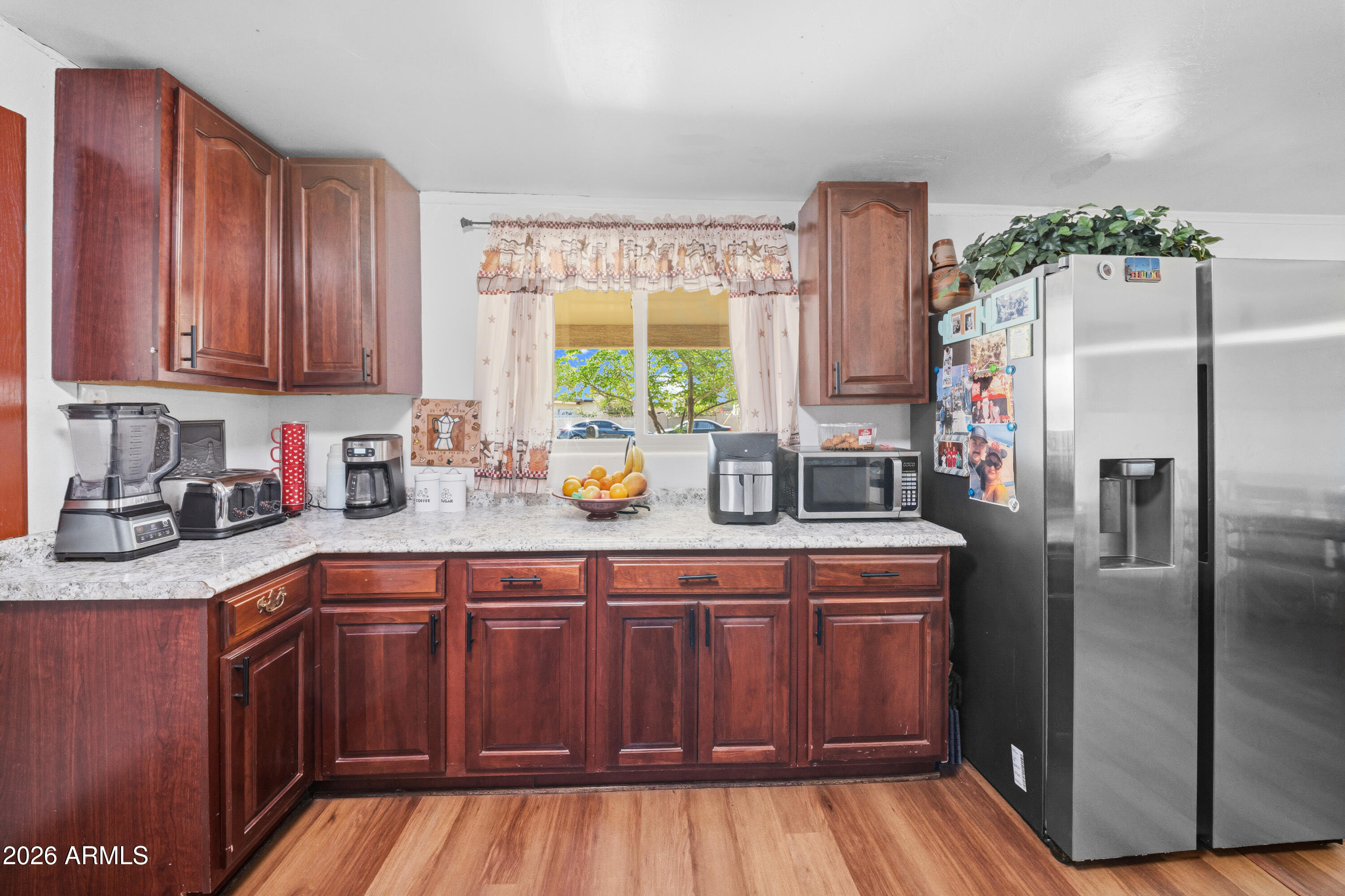 3902 West Monte Vista Road Phoenix, AZ 85009 - Photo 5 of 29 a kitchen with stainless steel appliances granite countertop a refrigerator a sink dishwasher and wooden cabinets with wooden floor
