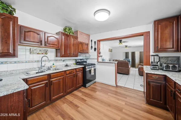 a kitchen with stainless steel appliances granite countertop wooden cabinets a sink dishwasher a stove and a refrigerator